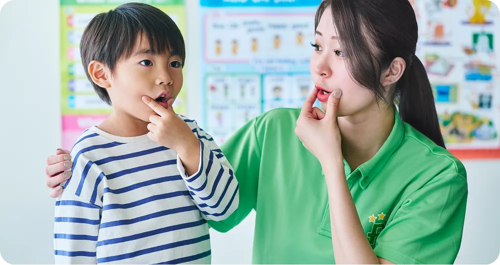 発音の練習をする男の子と講師の写真